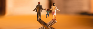 Statuette di una famiglia in equilibrio su forchette, simbolo di conciliazione tra vita familiare e lavoro