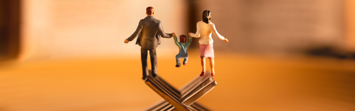 Statuette di una famiglia in equilibrio su forchette, simbolo di conciliazione tra vita familiare e lavoro